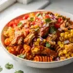 Creamy BBQ chicken pasta salad with corn and beans in a white bowl.