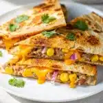 Crispy bean and cheese quesadilla with salsa and sour cream on wooden board