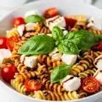 Colorful Caprese pasta salad with tomatoes, mozzarella, and basil in a bowl.