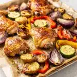 Crispy golden potatoes and tender chicken with roasted vegetables on a sheet pan.