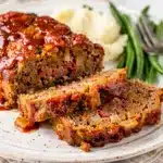 Classic homestyle meatloaf with a glossy glaze on a rustic wood table.