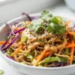 Cold sesame noodle salad with creamy peanut sauce and fresh colorful vegetables.