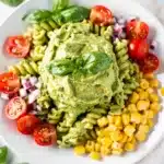 Creamy avocado pasta salad recipe with fusilli, tomatoes, corn, and red onion.
