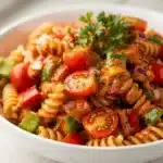 Creamy Cajun pasta salad with peppers, tomatoes, olives, and fresh parsley.