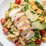Creamy chicken Caesar pasta salad with rotini, romaine, tomatoes, and Parmesan cheese.