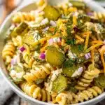Creamy dill pickle pasta salad with cheddar cheese and fresh dill garnish
