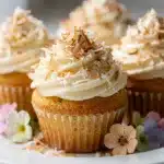 Coconut cupcake with creamy frosting and toasted coconut on rustic table