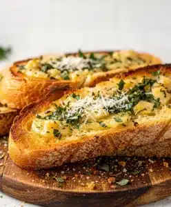 Golden brown garlic bread slices on a rustic wooden cutting board with parsley garnish