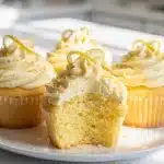 Homemade lemon cupcakes with creamy vanilla buttercream frosting on a bright plate.