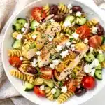 Lemon herb chicken pasta salad with fresh vegetables and feta cheese.