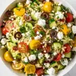 Bright lemon orzo salad recipe with fresh herbs and glossy vinaigrette in close up.