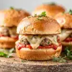 Mini Meatball Sliders bake in a dish with melted cheese and marinara sauce.