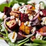 Roasted beet and goat cheese salad with walnuts and fresh greens plated