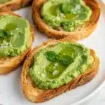 Bright green spring pea spread on toasted baguette crostini appetizer.