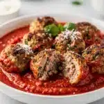 Golden brown baked turkey meatballs in a rustic marinara sauce with fresh basil.