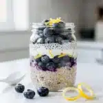 Creamy blueberry lemon overnight oats in a jar with fresh fruit.