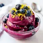 Refreshing blueberry lemonade sorbet in a bowl with fresh fruit garnish.