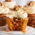 Moist carrot cake cupcakes with cream cheese frosting and walnut garnish.