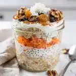 Creamy carrot cake overnight oats in a jar with rustic spoon and linen.