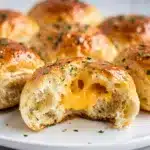 Golden brown cheddar herb dinner rolls with melted cheese and fresh herbs.