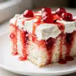 Moist yellow cake with vibrant red cherry jello pockets and whipped topping