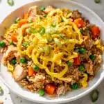 Golden scrambled eggs bind tender chicken fried rice with peas and carrots.