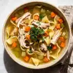 Homemade chicken noodle soup recipe in a rustic bowl with golden broth