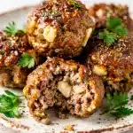 Classic ground beef meatballs in a creamy glossy sauce on a white plate