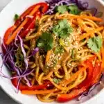 Cold sesame peanut noodle salad with creamy glossy sauce and fresh garnishes.
