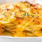 Creamy cheesy scalloped potatoes baked golden in a white ceramic dish