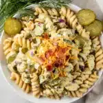 Creamy dill pickle pasta salad with rotini cheese and red onion in bowl
