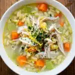 Creamy lemon chicken orzo soup in a white bowl with fresh parsley