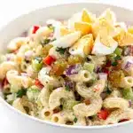 Creamy cold macaroni salad recipe with eggs and fresh vegetables in a bowl.