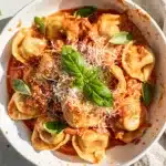 Creamy tomato basil tortellini recipe with cheese filling and glossy sauce.