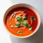 Creamy tomato soup recipe with fresh basil garnish and toasted bread.
