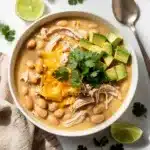 Creamy white chicken chili with avocado and beans in rustic bowl
