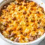 Creamy crockpot hashbrown casserole with turkey sausage and melted cheese.