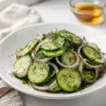 Crisp cucumber onion salad with tangy dressing and fresh dill sprigs.