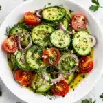 Fresh cucumber tomato salad recipe with red onion and herbs in olive oil dressing.
