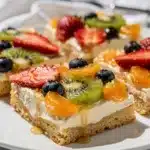 Colorful fruit pizza bars with soft sugar cookie base and cream cheese frosting