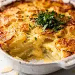 Creamy garlic Parmesan scalloped potatoes in a golden brown casserole dish.