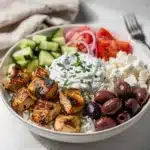 Greek chicken souvlaki bowls with creamy tzatziki and fresh vegetables plated close up.