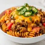 Creamy ground beef taco pasta with melted cheese and fresh cilantro garnish.