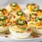 Creamy jalapeno popper deviled eggs with bacon and smoked paprika garnish.