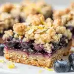 Lemon blueberry crumb bars with golden topping and vibrant purple filling.