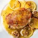 Crispy lemon garlic chicken thighs in a rustic cast iron skillet recipe.