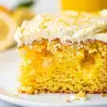 Moist lemon jello poke cake with creamy frosting and fresh blueberries garnish