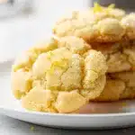 Lemon sugar cookies with sweet icing and sparkling sugar on a white plate.