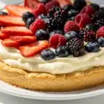 Colorful fresh berry lemon vanilla fruit pizza on rustic wooden table.