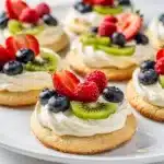 Mini fruit pizza cookies with creamy frosting and fresh colorful berries.